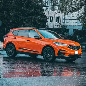 Orange SUV parked on wet city street.